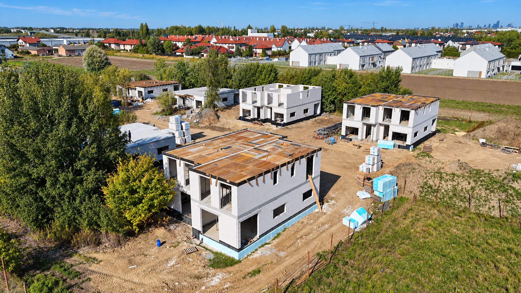 Lotniczy kadr na budowę — panorama osiedla z Warszawą w tle